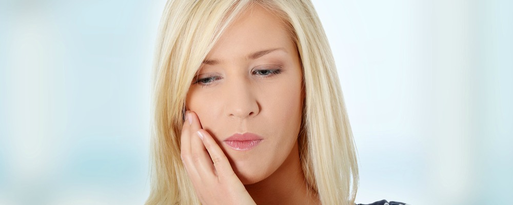 woman holding her jaw in pain before receiving TMJ treatment in richmond Indiana